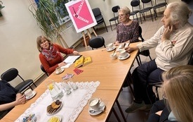 Wokół stołów siedzą uczestnicy dyskusji, rozmawiają.