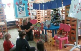Dzieci słuchają opowiadania bibliotekarki na temat renifer&oacute;w.