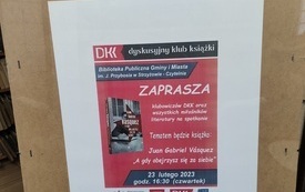 Na tablicy plakat informujący o spotkaniu, książka i logo DKK.
