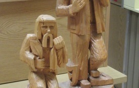 Dwie drewniane rzeźby przedstawiające mężczyzn - jeden ma w ręku pi&oacute;ro, drugi maskę teatralną