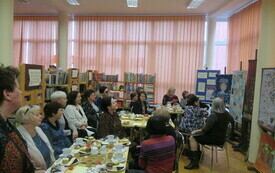 Uczestnicy spotkania, kobiety w różnym wieku siedzące przy stolikach kawowych.