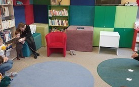 Dzieci wraz z dorosłymi trzymają w rękach kłębki włóczki. Przez pomieszczenie przeciągnięte są dwie nitki włóczki, na których znajdują się przyczepione papierowe myszy.