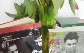 Na stole książki i wazon z kwiatami.
