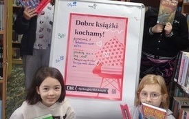 Pięć dziewczynek stoi przy plakacie Dyskusyjnych Klub&oacute;w Książki. Trzymają w rękach książki oraz zakładki. 