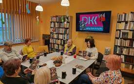 Kobiety wokół stołu siedzą i trzymają książki w rękach.