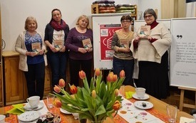 Pięć kobiet stoi przy plakacie Dyskusyjnych Klubów Książki  i trzyma w rękach książki