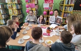 Kilkanaście osób siedzi przy stole, jedna z nich mówi reszta słucha.