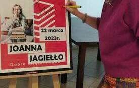 Kobieta podpisuje plakat Dyskusyjnych Klubów Książki.