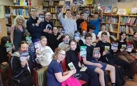 Grupa młodzieży siedzi z książkami w dłoniach