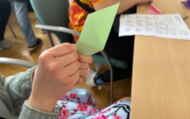 Zbliżenie na dłonie osoby składającej origami z zielonego papieru