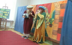 Dwoje aktor&oacute;w w egzotycznych, kolorowych strojach stoi na scenie