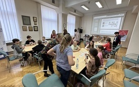 Uczestnicy turnieju siedzą przy stolikach i grają w grę Świteź. 