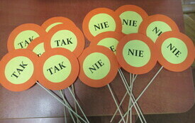 Czerwono-żółte tabliczki z napisem "tak" "nie" leżące na stole.