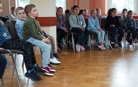 Kilka osób siedzi na krzesłach.