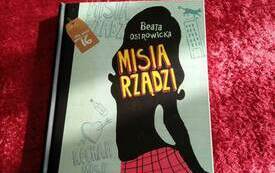 Książka z logo Dyskusyjnych Klubów Książki leży na stole.
