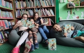 Dzieci leżą na podłodze i pozują do wspólnego zdjęcia, w dloniach trzymają książki.