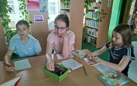 Dzieci malują, na stole leżą książki.
