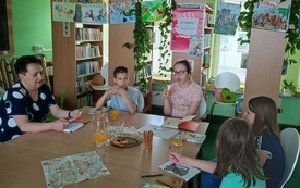 Kilkanaście osób siedzi przy stole i rozmawia.