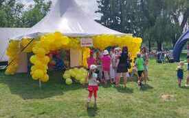 Namiot z ż&oacute;łtymi balonami i dzieci wok&oacute;ł niego. 