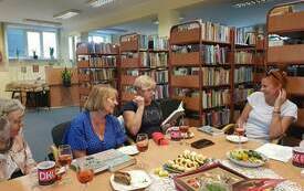 Uczestniczki spotkania DKK rozmawiają przy stole siedząc.