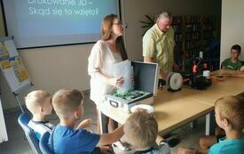 Mężczyzna i kobieta prezentują drukarkę 3D dzieciom. 
