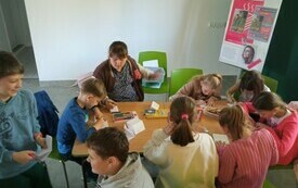 Grupa dzieci pracuje wykonuje prace plastyczne.
