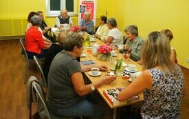 Kilka osób siedzi przy stole i rozmawia.