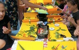 Grupa dzieci wykonuje przy stole kompozycje plastyczne z żywych roślin
