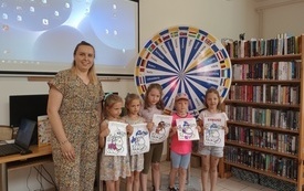 Grupa dzieci stoi prezentując do zdjęcia kolorowe rysunki