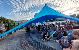 Niebieski namiot pod nim publiczność zgromadzona na spotkaniu w Ogrodach Bernardyńskich