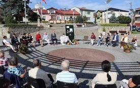 Kilkanaście os&oacute;b siedzi jedni czytają, inni słuchają. 