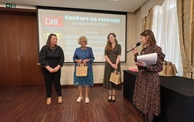 Cztery kobiety stoją na środku, jedna z trzyma mikrofon i mówi.