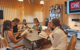 Grupa młodych dziewczyn i bibliotekarka trzymają w rękach książki.