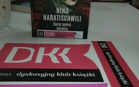 Okładka książki "Coraz mniej światła" oraz zakładki z logo Dyskusyjnym Klubem Książki.