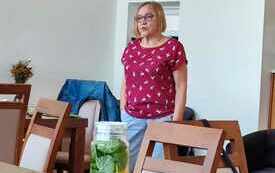 Kobieta stoi i patrzy w kierunku osób siedzących.