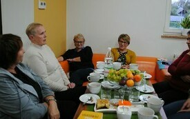 Kobieta mówi, reszta osób zgromadzonych w sali słucha.