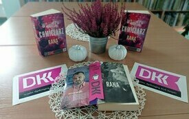 Okładka książki "Rana", loga DKK, wrzosy stojące na stole.