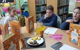 Dzieci siedzą i oglądają książki.