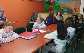Kilka dzieci siedzi na spotkaniu wokół stołu