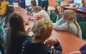 Kilka dzieci siedzi na spotkaniu wokół stołu