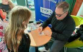 Mężczyzna pdpisuje dedykacje dla dziewczynki.