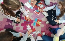 Dzieci układają puzzle z godłem Polski.