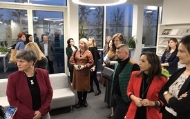 Uczestnicy konferencji kobiety i mężczyźni w różnym wieku zgromadzeni w bibliotece.