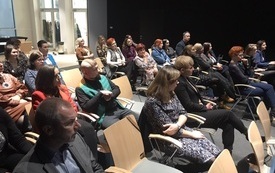 W sali zgromadzona publiczność siedząca na krzesełkach.