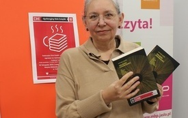 Bibliotekarka trzyma w rękach książki "Trudno powiedzieć" Łukasza Lamży.