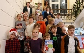 Laureaci konkursu, chłopcy i dziewczynki pozują do wsp&oacute;lnego zdjęcia na schodach w holu biblioteki.