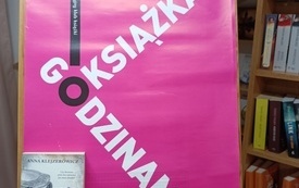 Plakat dkk z książką na sztaludze.