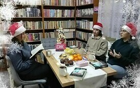 Trzy dziewczyny siedzą przy stole w czapkach Mikołaja.