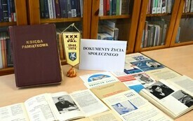 Na stoliku rozłożone książki, księga pamiątkowa i inne czasopisma.