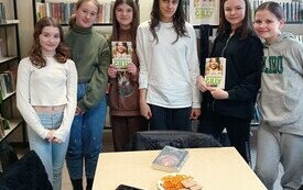 Młodzież pozuje do wspólnego zdjęcia, dziewczyny trzymają w ręku książki.